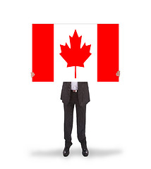 Image showing Smiling businessman holding a big card, flag of Canada