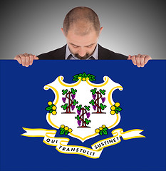 Image showing Smiling businessman holding a big card, flag of Connecticut