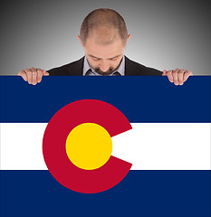 Image showing Smiling businessman holding a big card, flag of Colorado