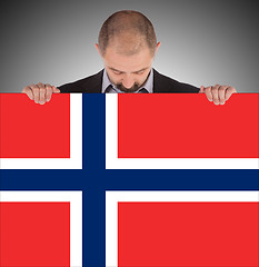 Image showing Smiling businessman holding a big card, flag of Norway