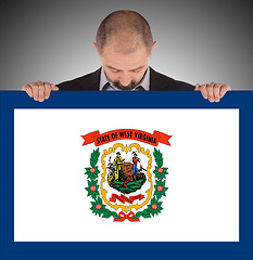 Image showing Smiling businessman holding a big card, flag of West Virginia