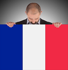 Image showing Smiling businessman holding a big card, flag of France