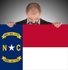 Image showing Smiling businessman holding a big card, flag of North Carolina