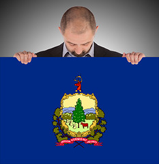 Image showing Smiling businessman holding a big card, flag of Vermont