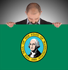 Image showing Smiling businessman holding a big card, flag of Washington