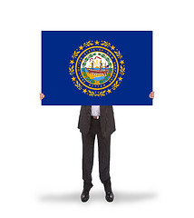 Image showing Smiling businessman holding a big card, flag of New Hampshire