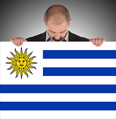 Image showing Smiling businessman holding a big card, flag of Uruguay