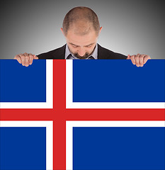 Image showing Smiling businessman holding a big card, flag of Iceland