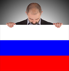 Image showing Smiling businessman holding a big card, flag of Russia