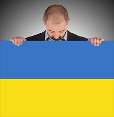 Image showing Smiling businessman holding a big card, flag of Ukraine