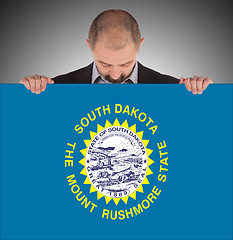 Image showing Smiling businessman holding a big card, flag of South Dakota