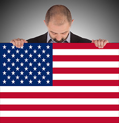 Image showing Smiling businessman holding a big card, flag of the United State