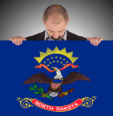 Image showing Smiling businessman holding a big card, flag of North Dakota