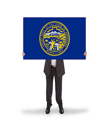 Image showing Smiling businessman holding a big card, flag of Nebraska