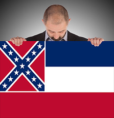 Image showing Smiling businessman holding a big card, flag of Mississippi