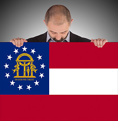 Image showing Smiling businessman holding a big card, flag of Georgia