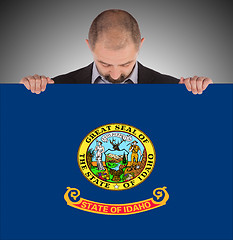 Image showing Smiling businessman holding a big card, flag of Idaho