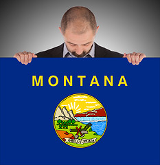 Image showing Smiling businessman holding a big card, flag of Montana