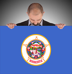 Image showing Smiling businessman holding a big card, flag of Minnesota