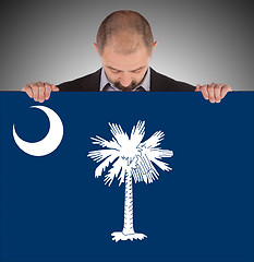 Image showing Smiling businessman holding a big card, flag of South Carolina