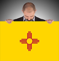 Image showing Smiling businessman holding a big card, flag of New Mexico