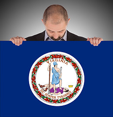 Image showing Smiling businessman holding a big card, flag of Virginia