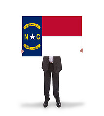 Image showing Smiling businessman holding a big card, flag of North Carolina