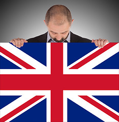 Image showing Smiling businessman holding a big card, flag of the United Kingd