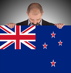 Image showing Smiling businessman holding a big card, flag of New Zealand