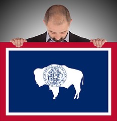 Image showing Smiling businessman holding a big card, flag of Wyoming