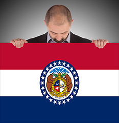 Image showing Smiling businessman holding a big card, flag of Missouri