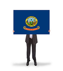 Image showing Smiling businessman holding a big card, flag of Idaho