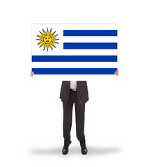 Image showing Smiling businessman holding a big card, flag of Uruguay