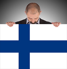 Image showing Smiling businessman holding a big card, flag of Finland