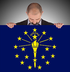 Image showing Smiling businessman holding a big card, flag of Indiana