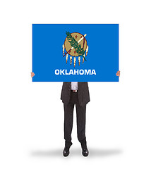 Image showing Smiling businessman holding a big card, flag of Oklahoma