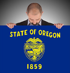 Image showing Smiling businessman holding a big card, flag of Oregon