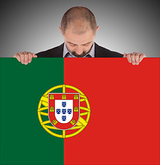 Image showing Smiling businessman holding a big card, flag of Portugal