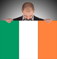 Image showing Smiling businessman holding a big card, flag of Ireland