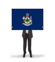 Image showing Smiling businessman holding a big card, flag of Maine