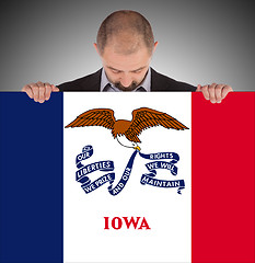 Image showing Smiling businessman holding a big card, flag of Iowa