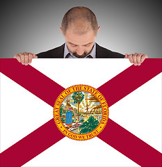 Image showing Smiling businessman holding a big card, flag of Florida