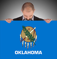 Image showing Smiling businessman holding a big card, flag of Oklahoma