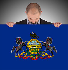 Image showing Smiling businessman holding a big card, flag of Pennsylvania