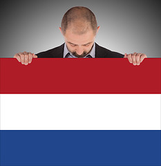 Image showing Smiling businessman holding a big card, flag of the Netherlands