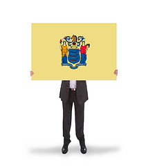 Image showing Smiling businessman holding a big card, flag of New Jersey