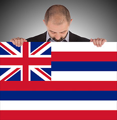 Image showing Smiling businessman holding a big card, flag of Hawaii