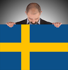 Image showing Smiling businessman holding a big card, flag of Sweden