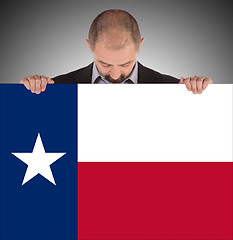 Image showing Smiling businessman holding a big card, flag of Texas