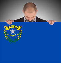 Image showing Smiling businessman holding a big card, flag of Nevada